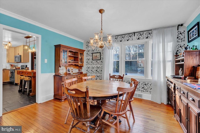 dining room with a notable chandelier, light hardwood / wood-style flooring, and ornamental molding