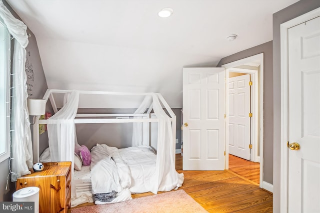 bedroom with wood-type flooring and vaulted ceiling