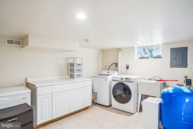 clothes washing area featuring separate washer and dryer, electric panel, cabinets, and light tile patterned flooring