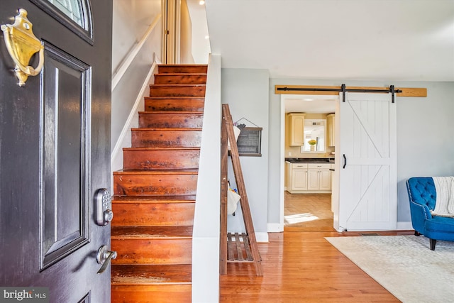 stairway featuring wood-type flooring and a barn door