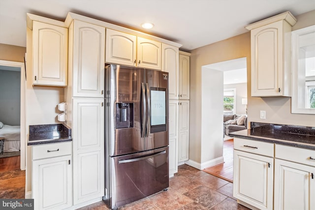 kitchen featuring dark stone countertops, cream cabinetry, and stainless steel fridge with ice dispenser