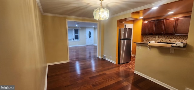 corridor with crown molding, an inviting chandelier, and dark wood-type flooring