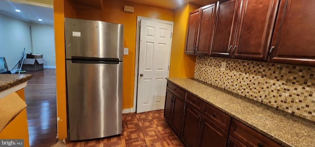 kitchen featuring tasteful backsplash, stainless steel fridge, and light stone countertops