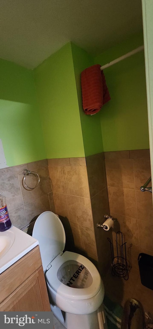 bathroom featuring tile walls, vanity, and toilet