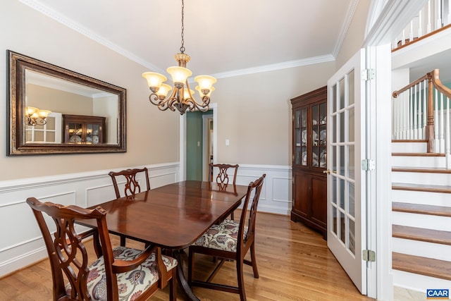 dining space featuring crown molding, a notable chandelier, and light hardwood / wood-style flooring