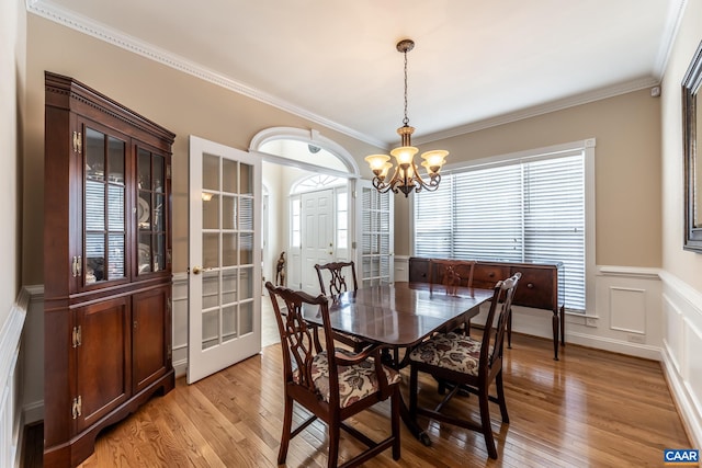 dining space with ornamental molding, light wood-type flooring, and a chandelier