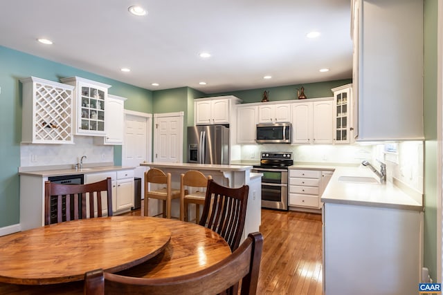 kitchen featuring a kitchen island, appliances with stainless steel finishes, sink, wine cooler, and white cabinets