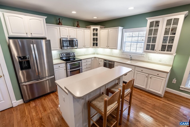 kitchen with sink, stainless steel appliances, light hardwood / wood-style floors, decorative backsplash, and white cabinets