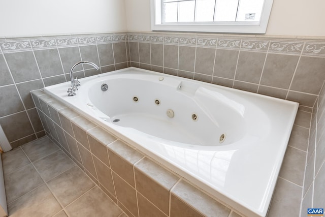 bathroom with a relaxing tiled tub and tile patterned floors