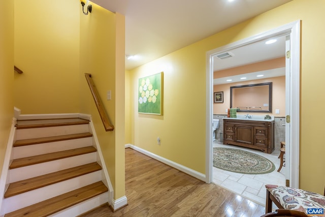 staircase with hardwood / wood-style floors and sink