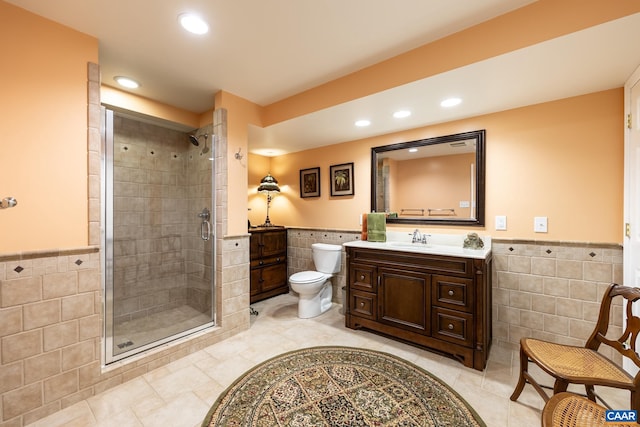 bathroom with a shower with door, vanity, tile walls, and toilet