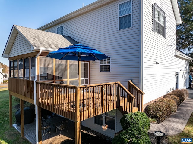 rear view of house with a wooden deck and a sunroom