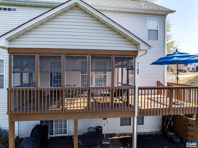 rear view of house featuring a wooden deck and a sunroom