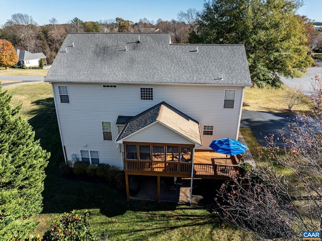 rear view of house with a sunroom, a deck, and a lawn