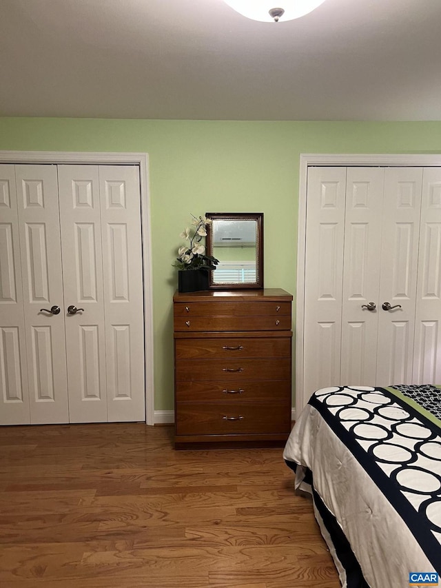 bedroom with hardwood / wood-style flooring and multiple closets