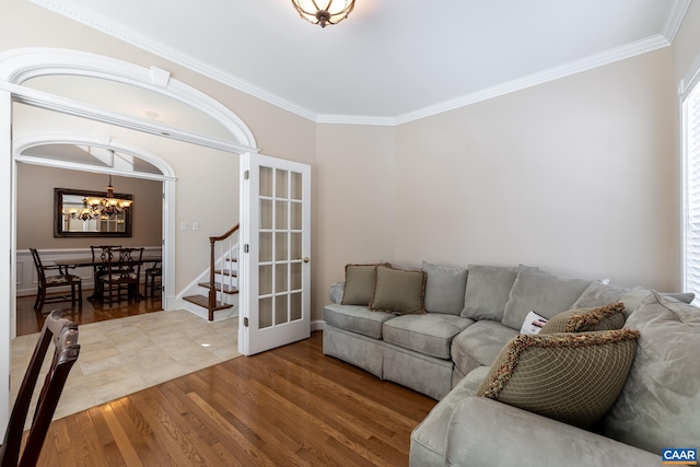 living room with crown molding, wood-type flooring, an inviting chandelier, and french doors