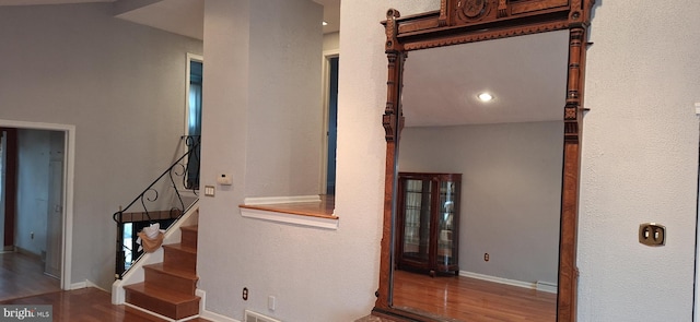 staircase featuring hardwood / wood-style flooring and lofted ceiling