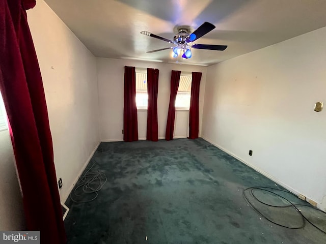 unfurnished room with ceiling fan and dark carpet