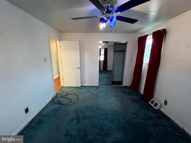 unfurnished bedroom featuring ceiling fan, dark carpet, and a closet