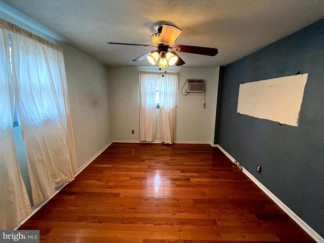 unfurnished room with ceiling fan, dark wood-type flooring, a textured ceiling, and a wall mounted air conditioner