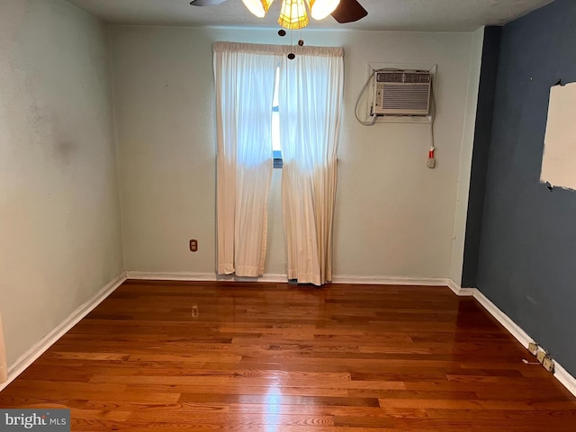 unfurnished room with ceiling fan, wood-type flooring, and a wall mounted air conditioner