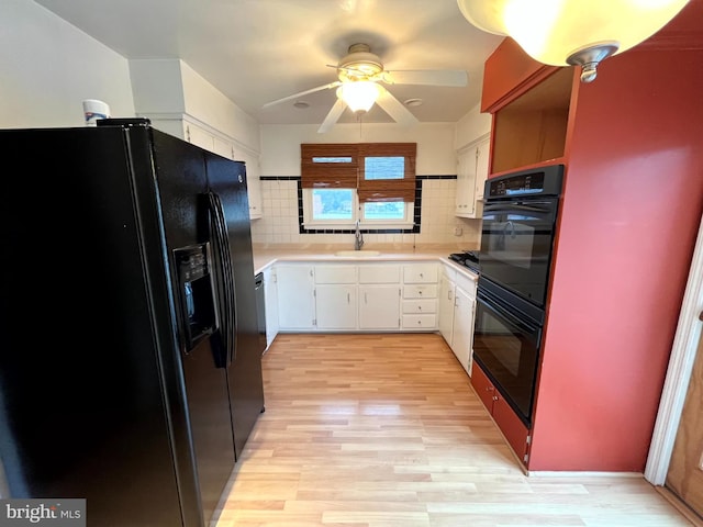 kitchen with black appliances, decorative backsplash, light wood-type flooring, white cabinets, and sink