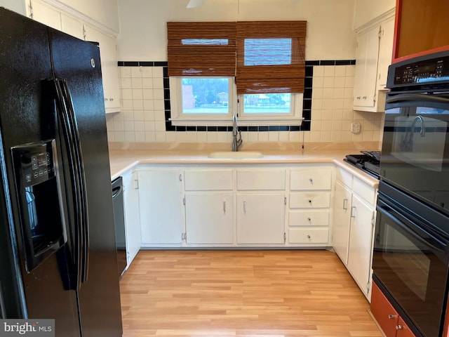 kitchen featuring black appliances, white cabinetry, tasteful backsplash, sink, and light wood-type flooring