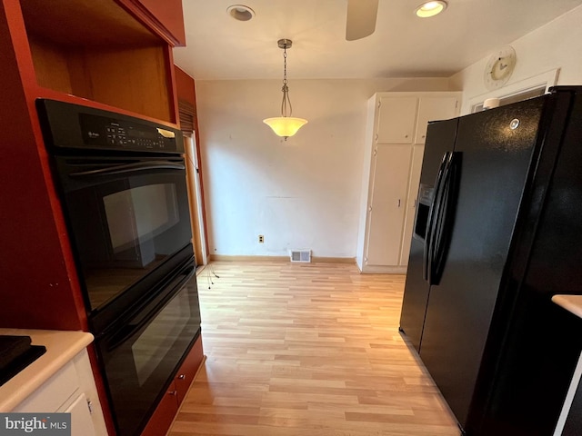 kitchen featuring white cabinets, decorative light fixtures, light hardwood / wood-style flooring, ceiling fan, and black fridge with ice dispenser