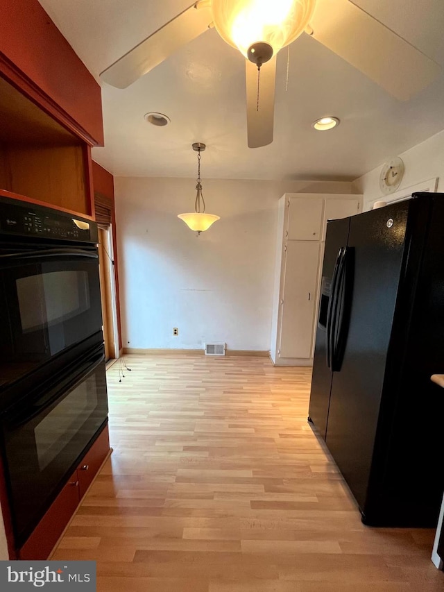 kitchen with black appliances, decorative light fixtures, white cabinetry, and light hardwood / wood-style floors