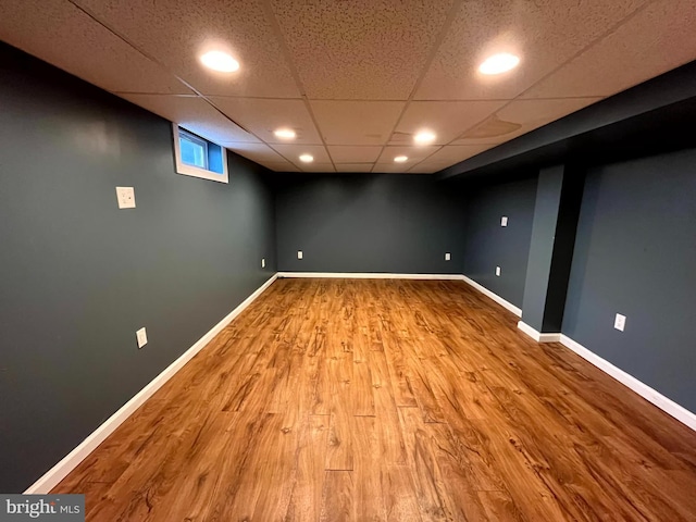 basement with hardwood / wood-style floors and a paneled ceiling