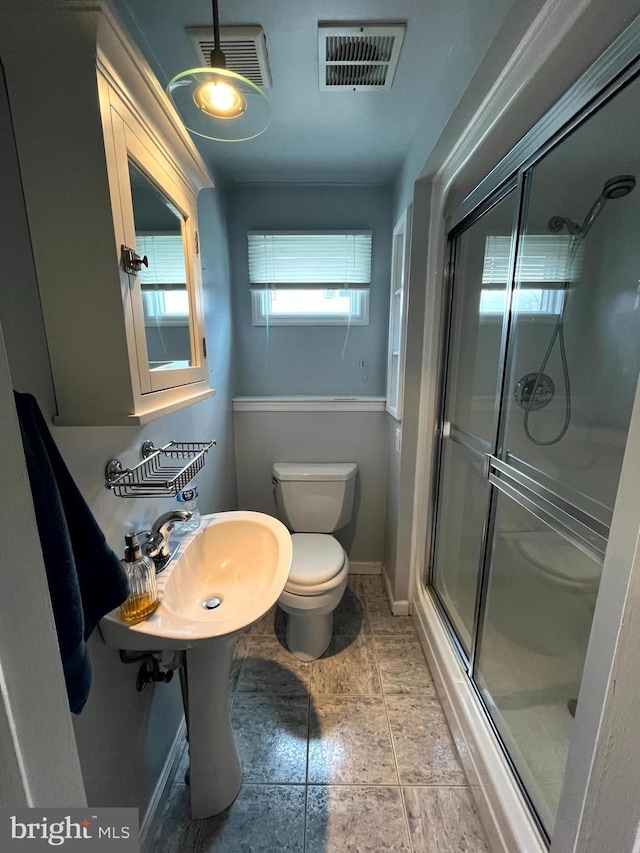 bathroom with a shower with shower door, toilet, and tile patterned flooring