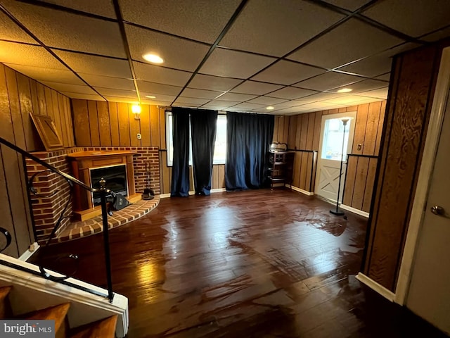 unfurnished living room featuring a wealth of natural light, a drop ceiling, and a fireplace