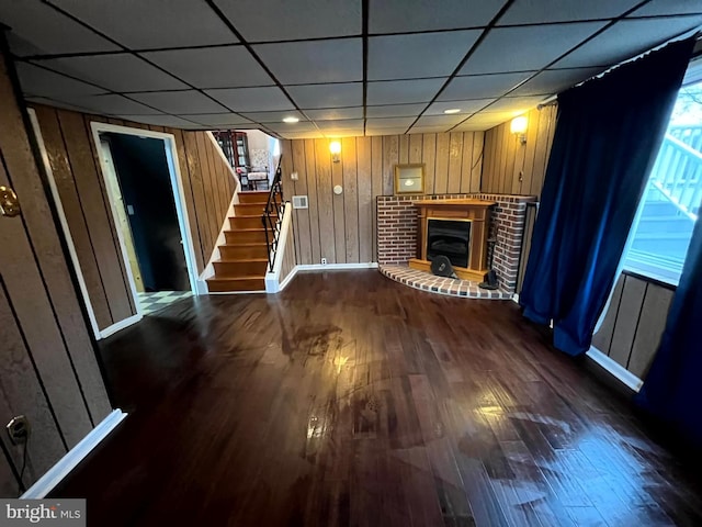 unfurnished living room featuring wood walls, dark wood-type flooring, and a fireplace