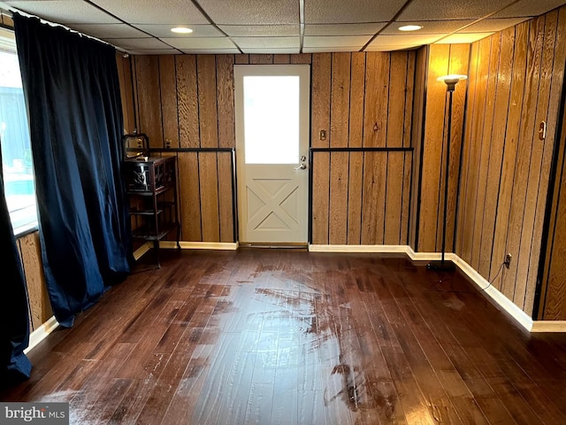 interior space featuring wood walls, a drop ceiling, and dark hardwood / wood-style floors