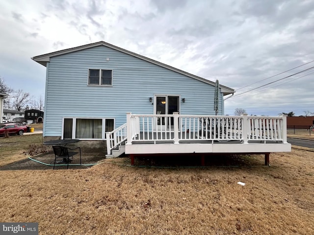 rear view of house featuring a wooden deck and a yard