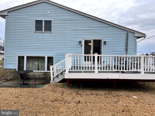 rear view of house with a deck and a yard