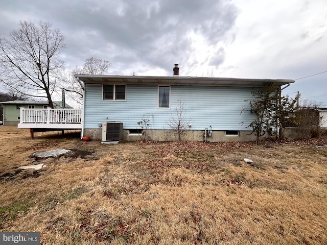 back of property with central AC unit, a wooden deck, and a yard