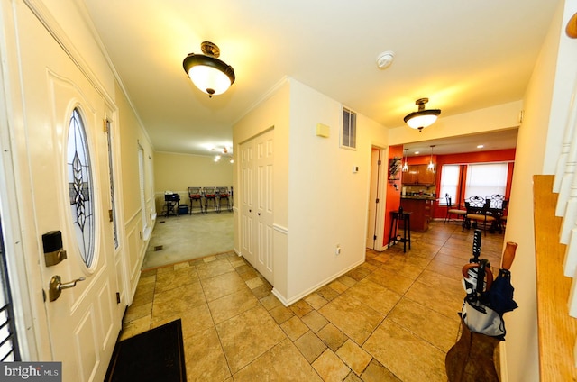 hallway with crown molding and light tile patterned flooring