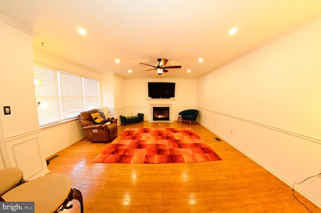 unfurnished living room with light hardwood / wood-style flooring, ornamental molding, and ceiling fan