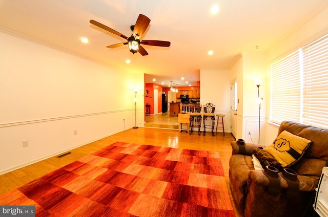 living room with crown molding, light hardwood / wood-style flooring, and ceiling fan