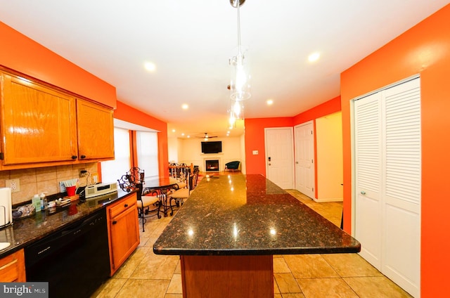 kitchen featuring decorative light fixtures, dark stone countertops, dishwasher, a kitchen island, and decorative backsplash