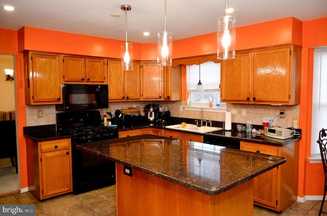 kitchen with decorative light fixtures, sink, backsplash, a center island, and black appliances