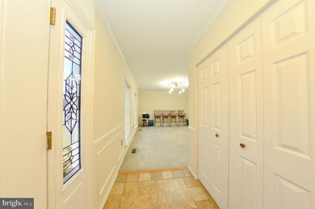 hall with ornamental molding and light carpet