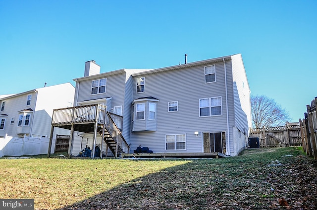 rear view of house with central AC, a wooden deck, and a lawn