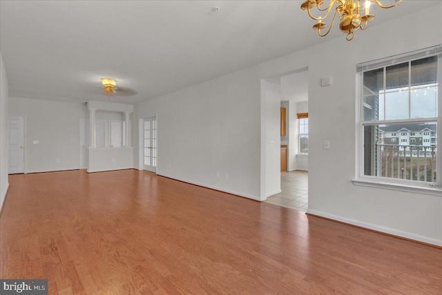 unfurnished room with a chandelier and light wood-type flooring