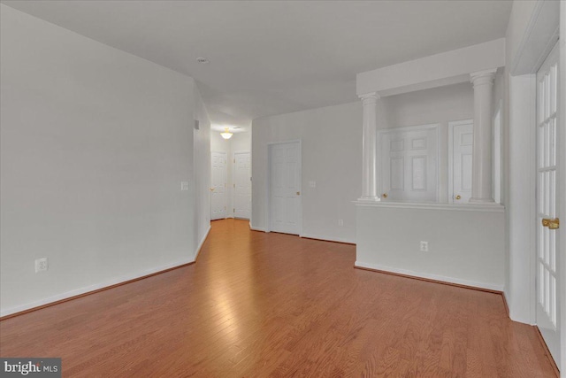 empty room with decorative columns and light wood-type flooring