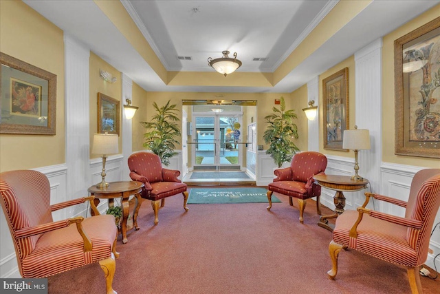 living area featuring crown molding, a tray ceiling, and carpet flooring