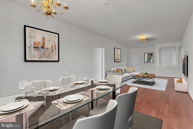 dining space with an inviting chandelier, hardwood / wood-style floors, and ornate columns