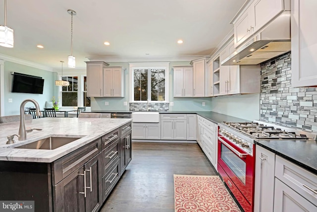 kitchen featuring hanging light fixtures, an island with sink, stove, and sink