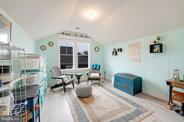 living area featuring vaulted ceiling and light hardwood / wood-style floors